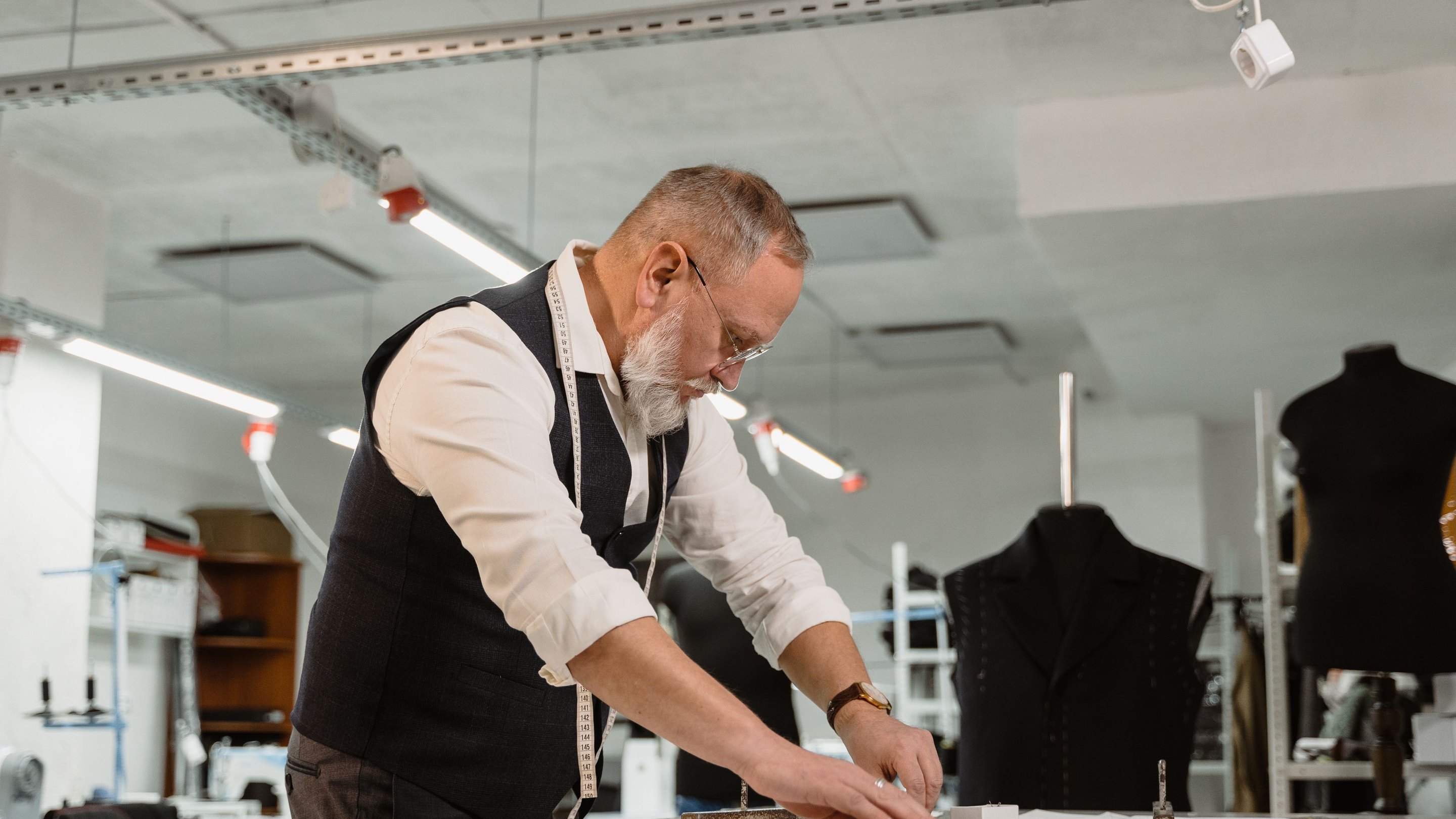 A cutter working cloth by hand at an atelier table