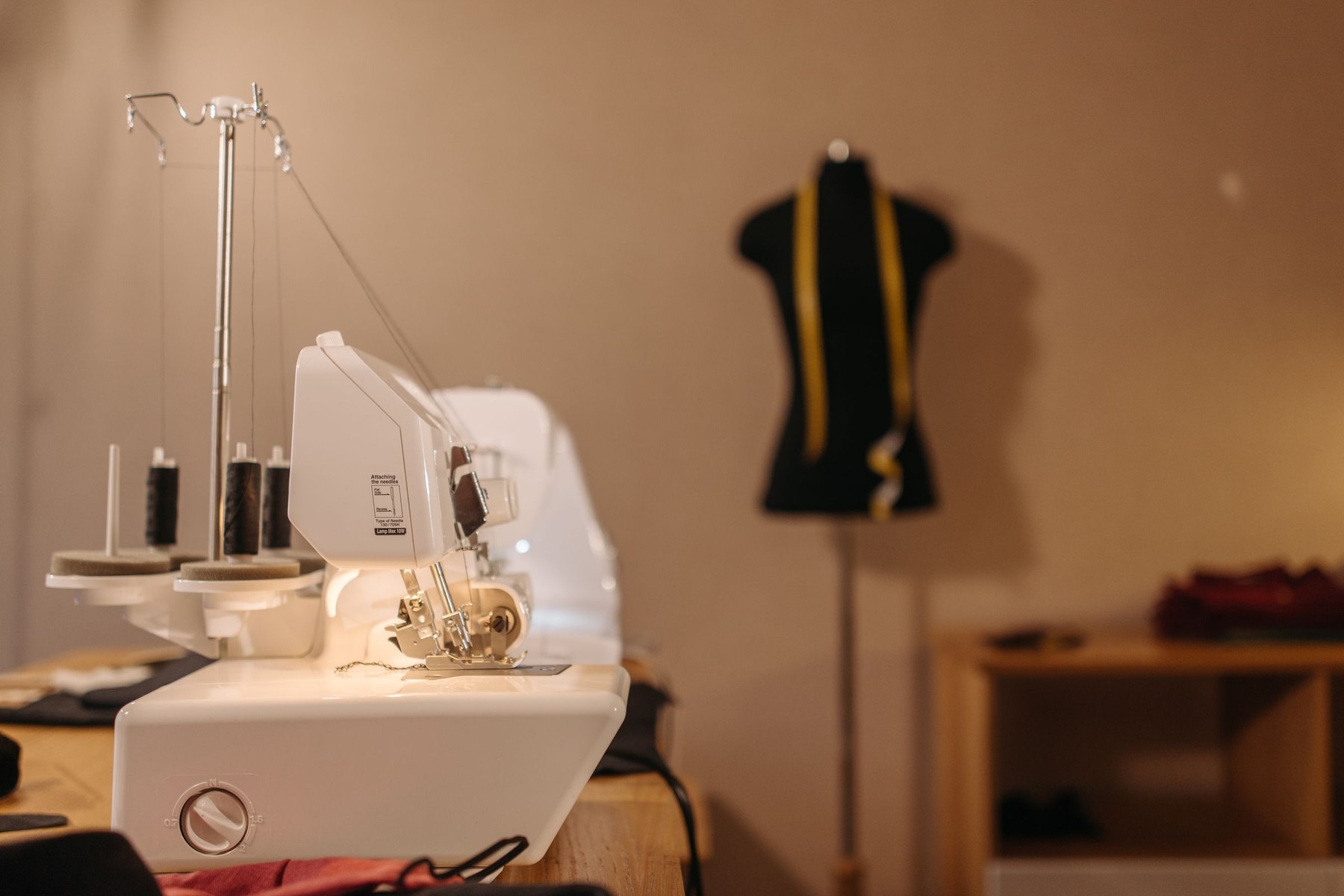 A sewing machine on the workbench beside a half-made jacket