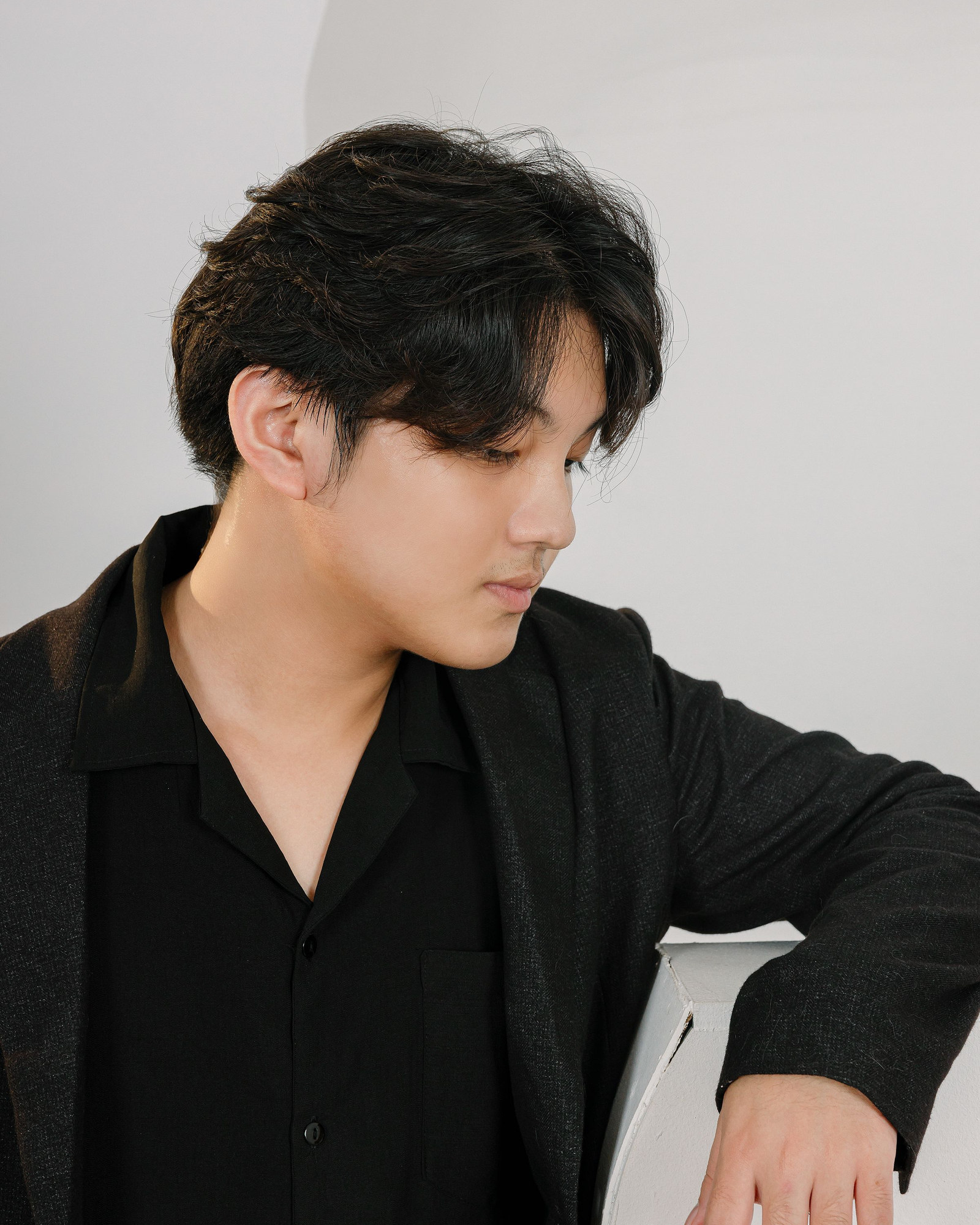 Man wearing a black tailored jacket against a pale studio wall